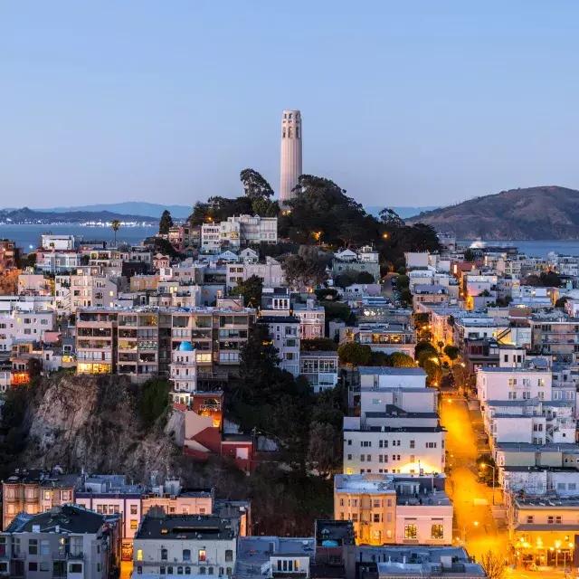 La Coit Tower de San Francisco au crépuscule, 前面是灯火通明的街道，后面是贝博体彩app湾区.